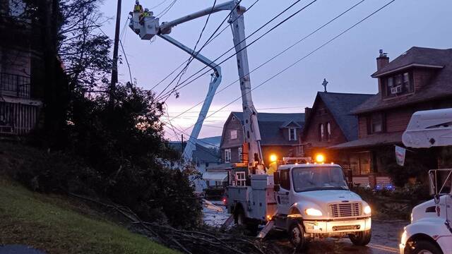 Crews work to clean up a tangled mess of downed trees and power lines on Main Street, Nanticoke, late Thursday evening.
                                 Margaret Roarty | Times Leader